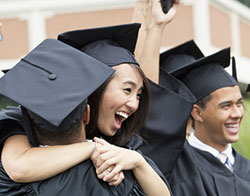 smiling teens in caps and gowns