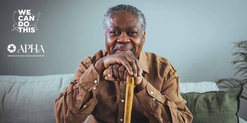 Older smiling Black man sitting and holding a cane