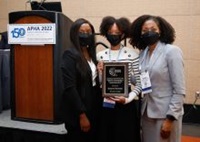 Three attendees at APHA2022 posing with an award 