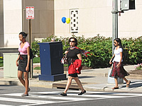 Three female pedestrians crossing a street.