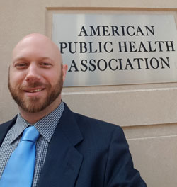 Smiling Ben King in front of American Public Health Association sign