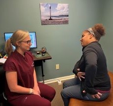A patient sitting on an exam table speaking to a chiropractor