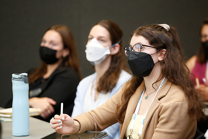 A trio of attendees watch a session presentation. 