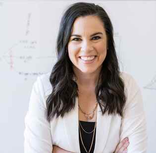 Photo of Katelyn Jetelina in front of whiteboard with charts