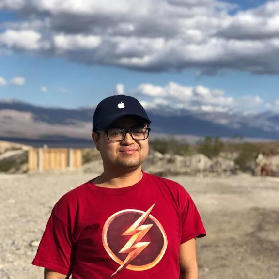 Dennis an Asian American man outdoors with a red shirt on and a black hat