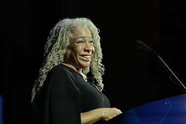 Deanna J. Wathington stands at a lectern and smiles broadly. 