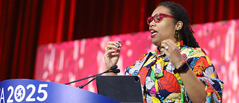 New APHA President Nandi Marshall wears a colorful dress and speaks from behind a lectern on a large stage.