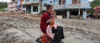 A woman weeps amid the damage of a flood in a Nepal river valley in August 2026.