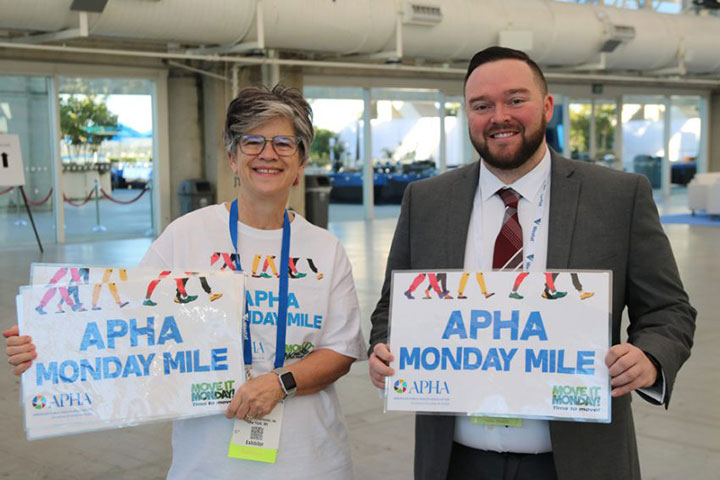 smiling man and woman holding Monday Mile signs