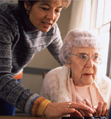 Nurse helping older woman at a computer