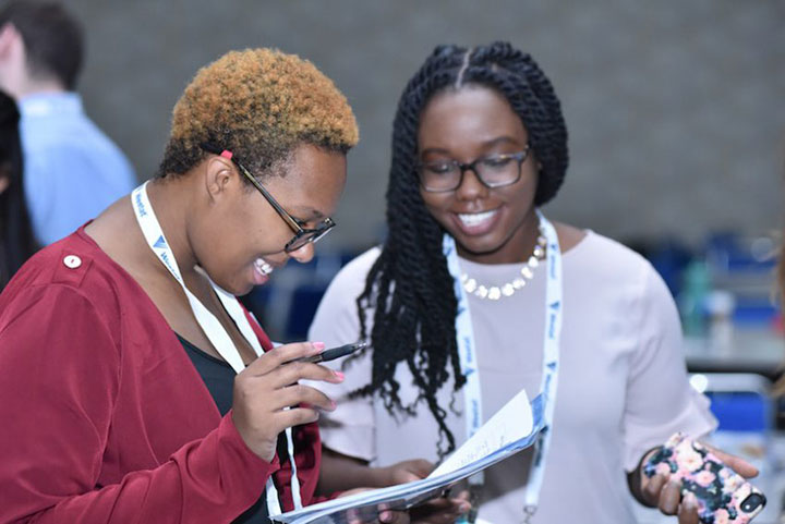 Smiling women looking at Annual Meeting program
