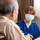 masked health worker speaking with older man