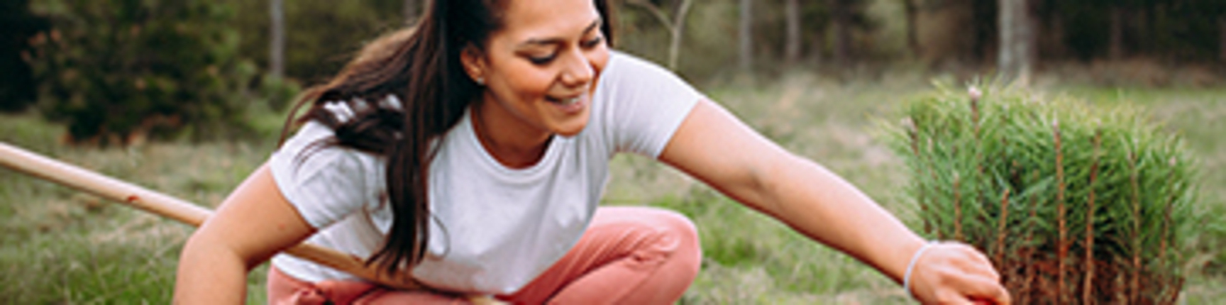 A woman smiles while working in a community garden