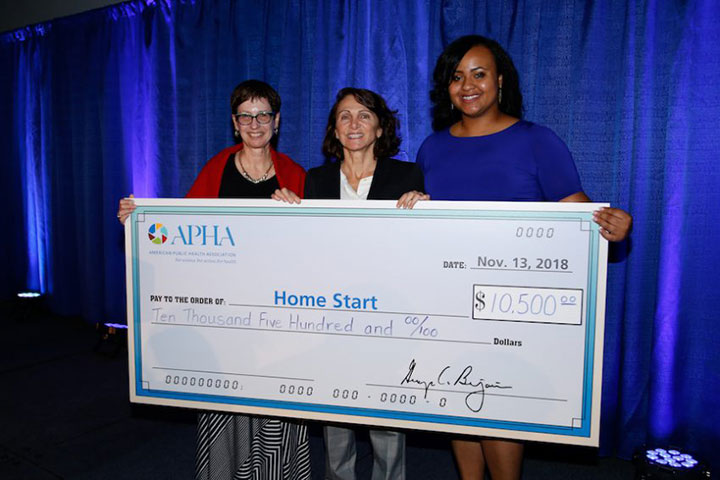 three smiling women holding huge $10,500 check to Home Start