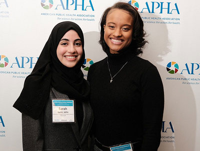 two women smiling in front of APHA logo backdrop