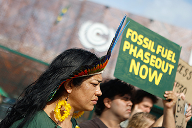 Protestors carry sign saying "Fossil Fuel Phase Out Now"