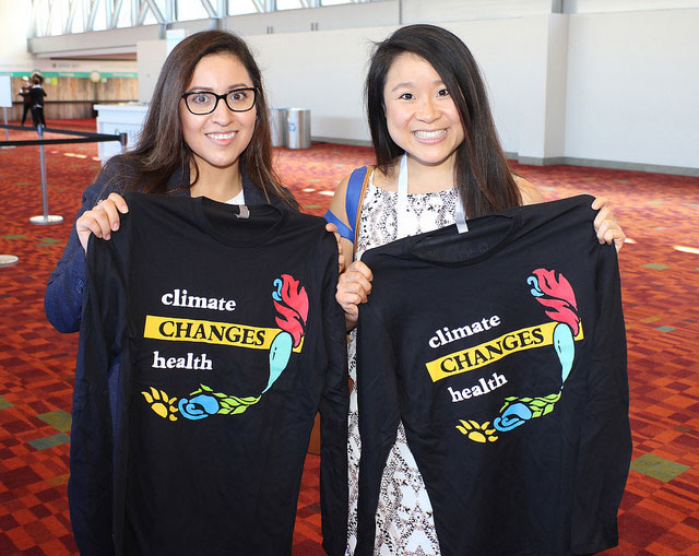 two smiling women holding up Climate Changes Health T-shirts