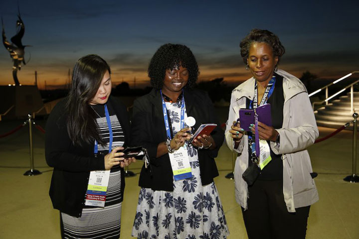 three women smiling and looking at phones