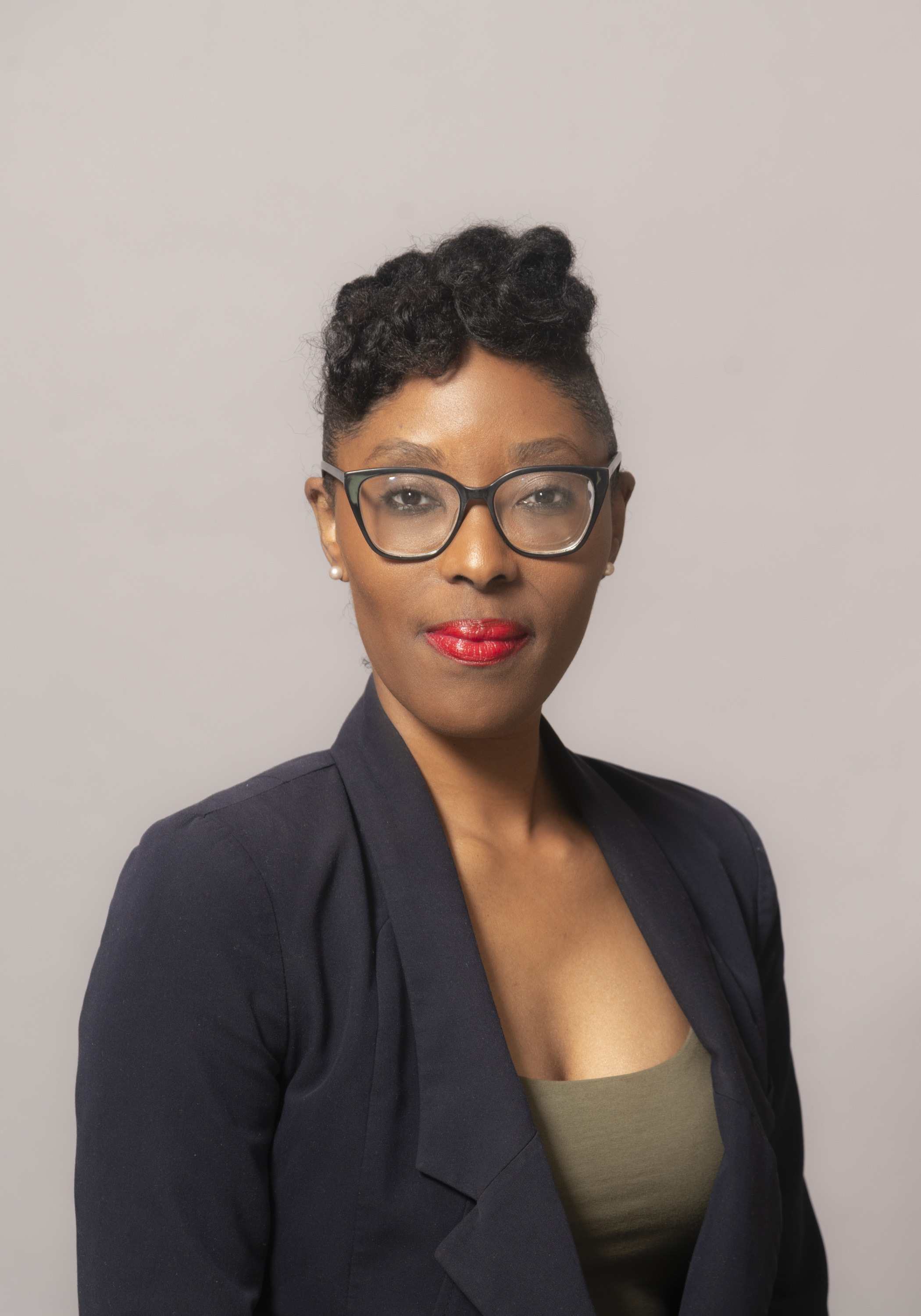 Black woman with glasses and red lipstick wearing a suit 