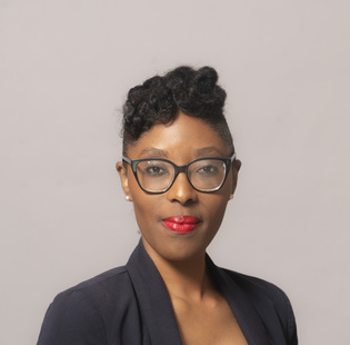 Black woman with glasses and red lipstick wearing a suit 