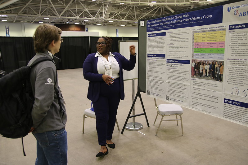 Man with backpack and woman giving poster presentation at APHA annual meeting