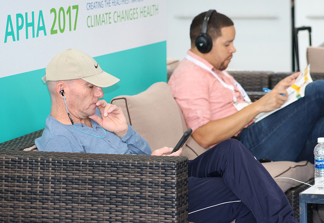 men reading Annual Meeting program while seated on couch 