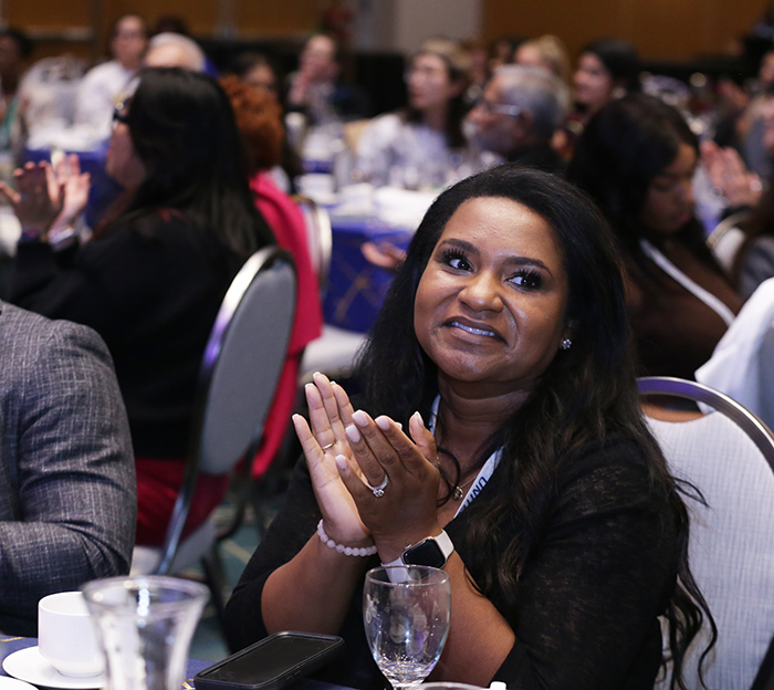 A woman sitting at a table claps. 