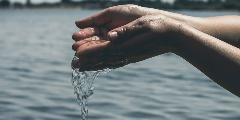 water running through outstretched hands