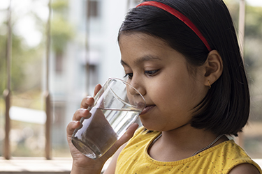 A girl sips water from a glass