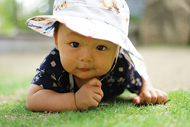 Baby wearing a hat crawls on the grass