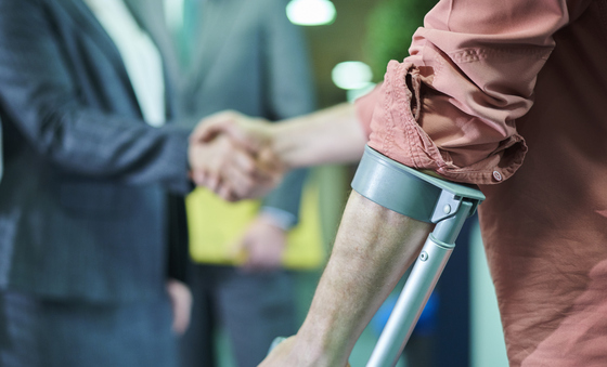 Two men shaking hands, one using a support