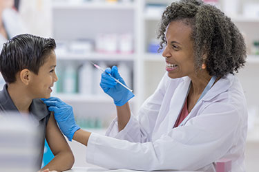 smiling health worker giving vaccination to smiling boy
