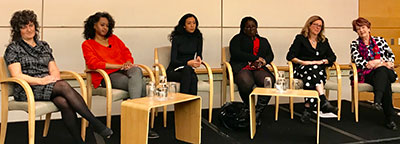six women seated on stage