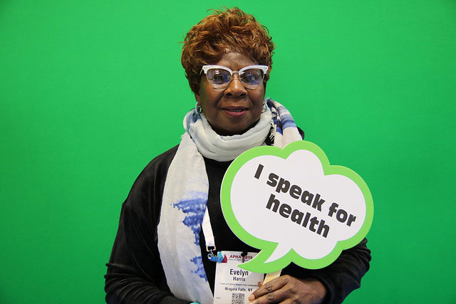 woman holding I speak for health sign