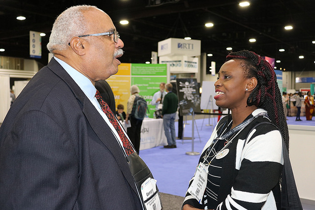 Georges Benjamin speaking with woman in Expo Hall