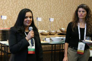 Surili Patel speaks into microphone as another woman looks on