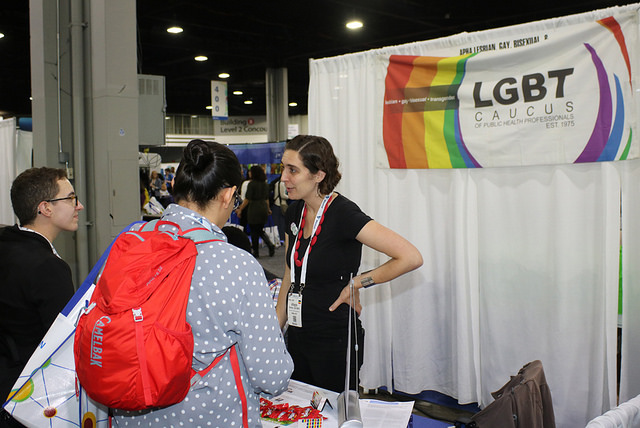 two attendees talking with woman at LGBT booth