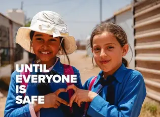Two little kids in front of shelters wearing blue shirts making a heart with their hands