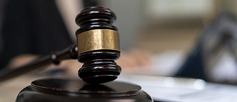 A stylized gavel rests on a court desk