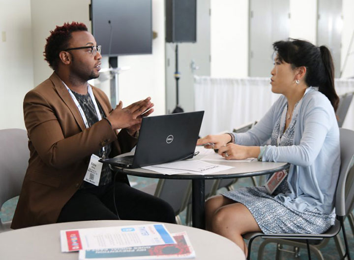 man with laptop speaking to woman