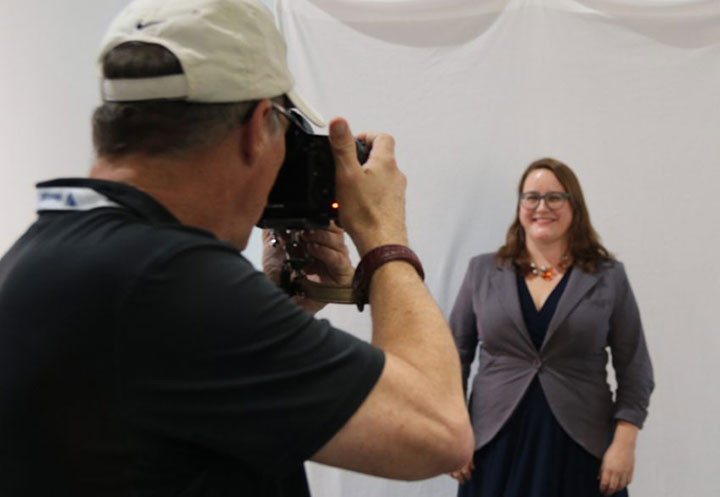 Joe Center shooting woman's photo as she smiles for the camera
