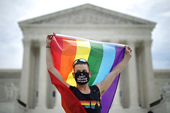woman holding rainbow flag in front of Supreme Court