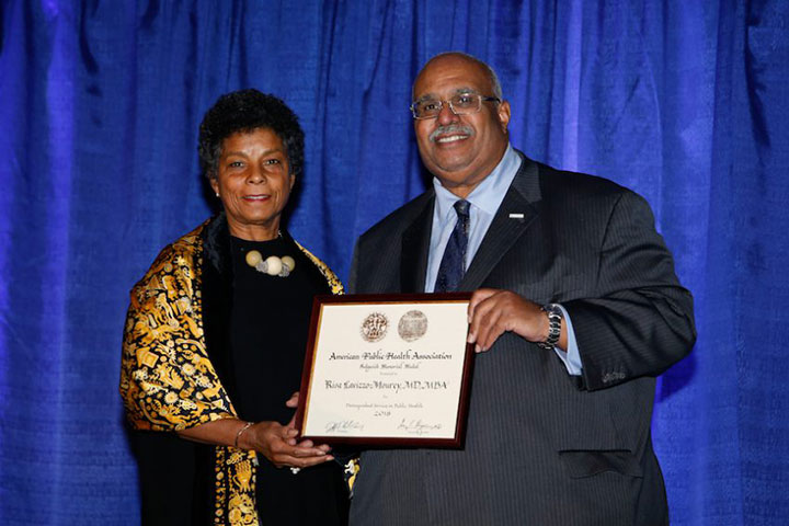 Smiling Georges Benjamin presenting award to smiling woman