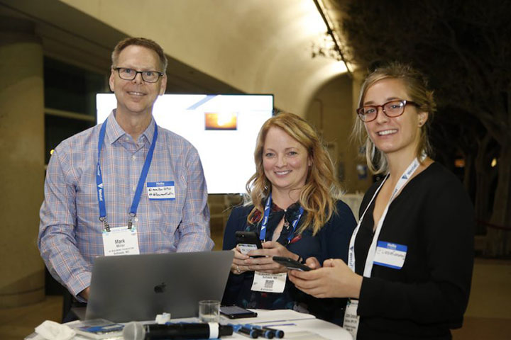 man with laptop and women with phones smiling