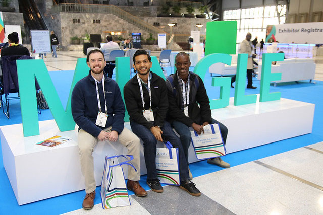 three smiling men with Annual Meeting tote bags