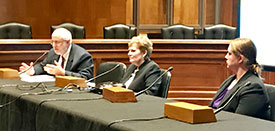 man speaking at table as two women look on