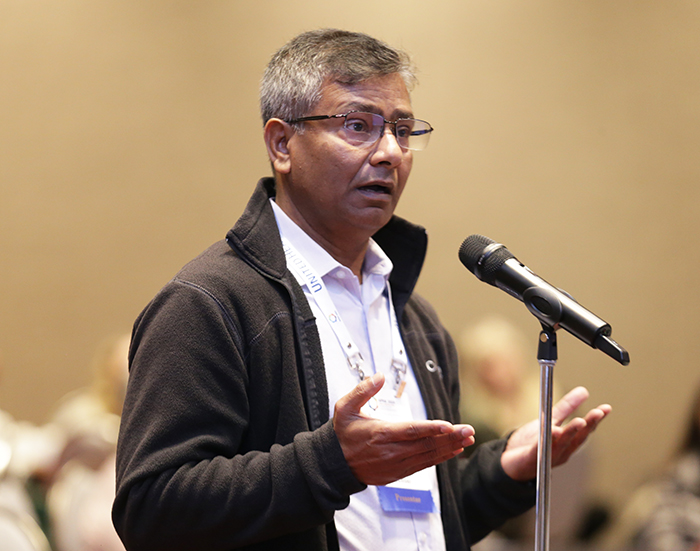 A man stands at a microphone and asks a question toward the front of the room. 
