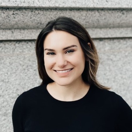 White woman smiling at the camera with brown hair wearing a black shirt