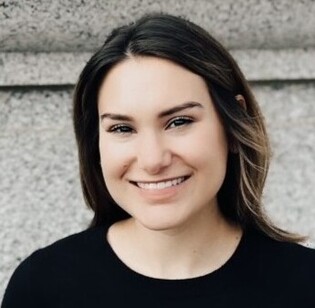 White woman smiling at the camera with brown hair wearing a black shirt