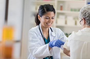 pharmacist bandaging woman's arm